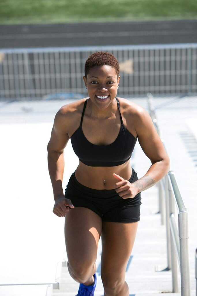 Fit woman with short hair jogging outdoors, showing strength and happiness.